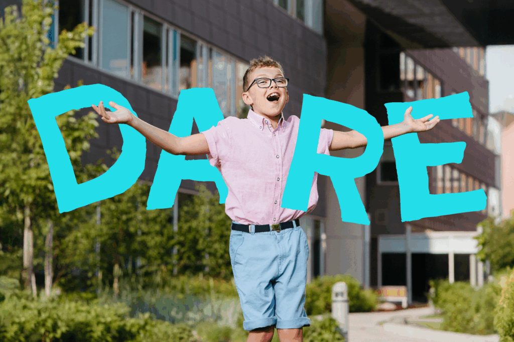 A young boy joyfully spreading his arms outdoors in front of Holland Bloorview