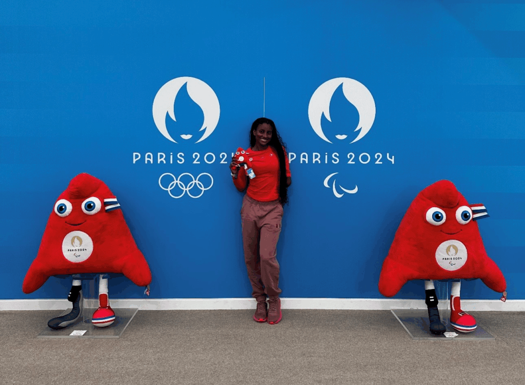 A young athlete standing in front of a blue wall at the Paris Paralympics