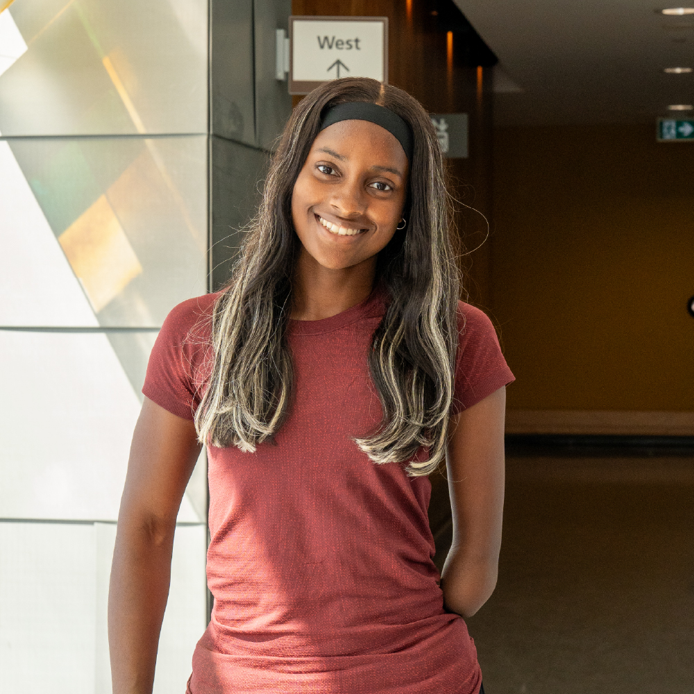 A young woman smiles while standing near an elevator
