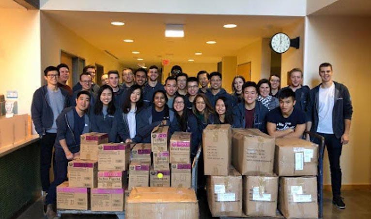 Group smiling in front of packed cardboard boxes