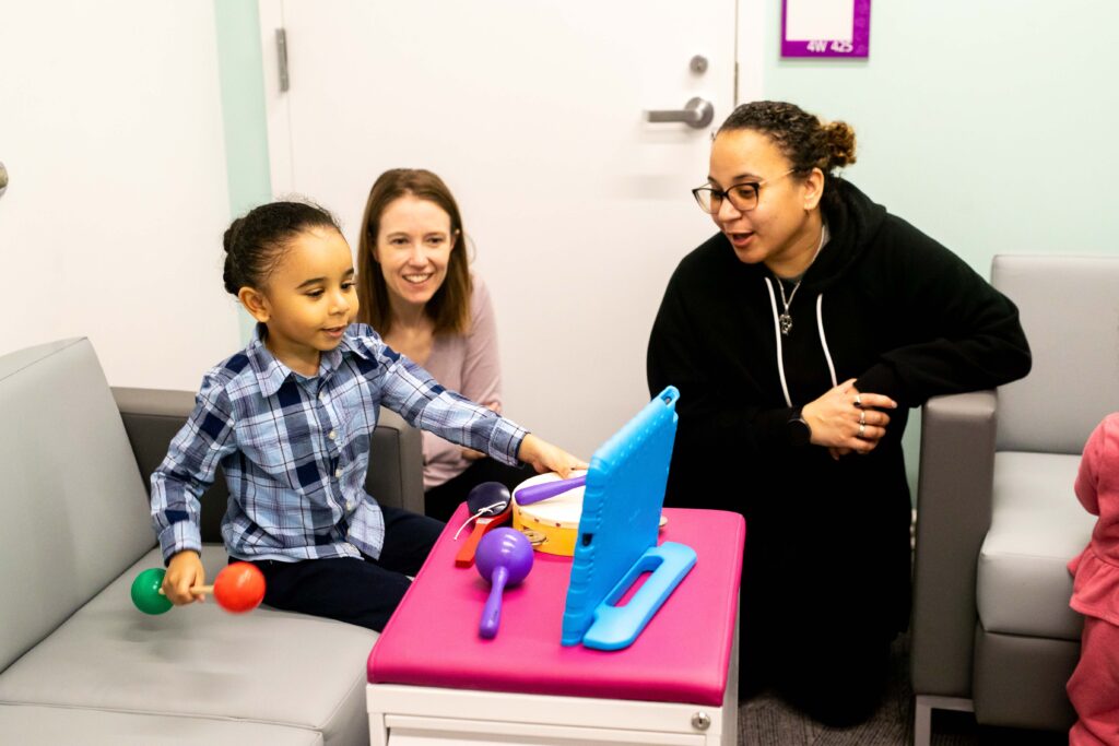A child and two adults play a video game on a blue tablet