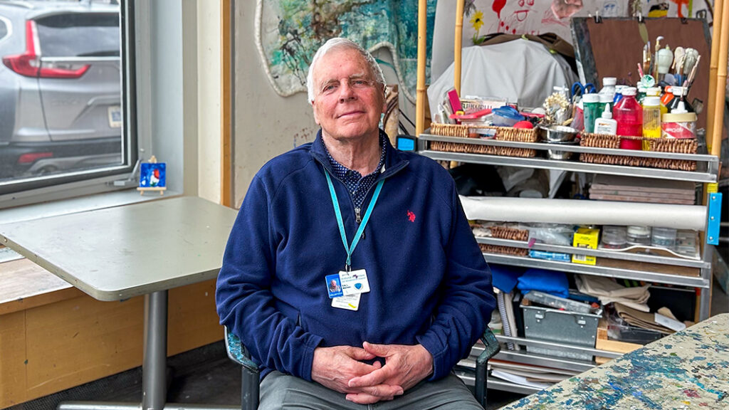 A man sits in an art therapy room with his hands in his lap