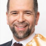 Adam Hagarty An adult wears a suit in front of a white background