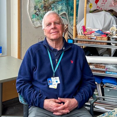 A man sits in an art therapy room with his hands in his lap