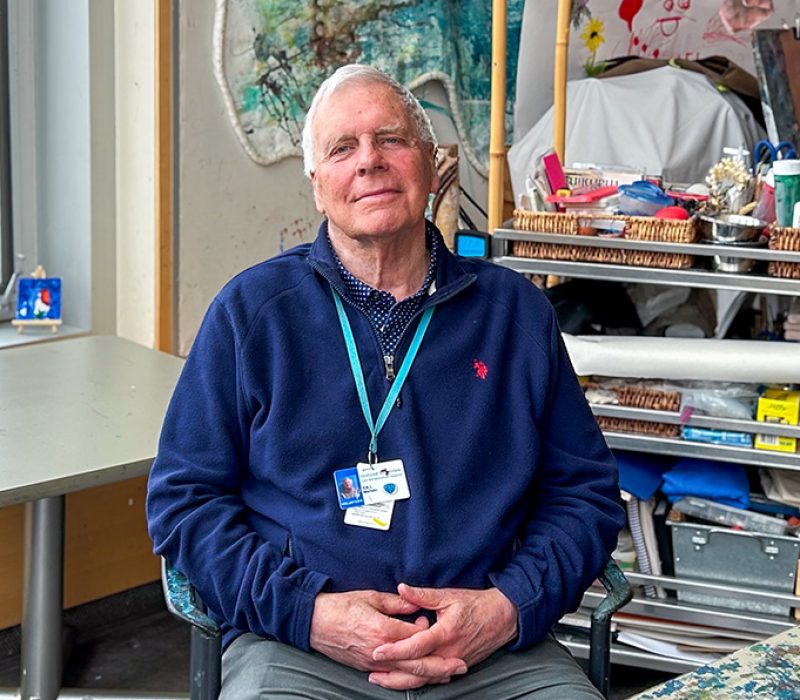 A man sits in an art therapy room with his hands in his lap