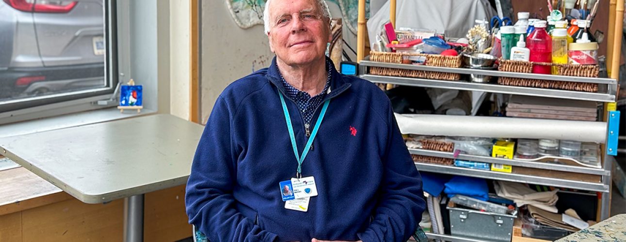 A man sits in an art therapy room with his hands in his lap