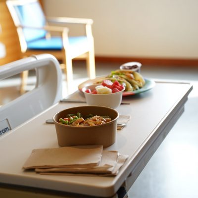 Bowls of food placed on a table in a hospital room.