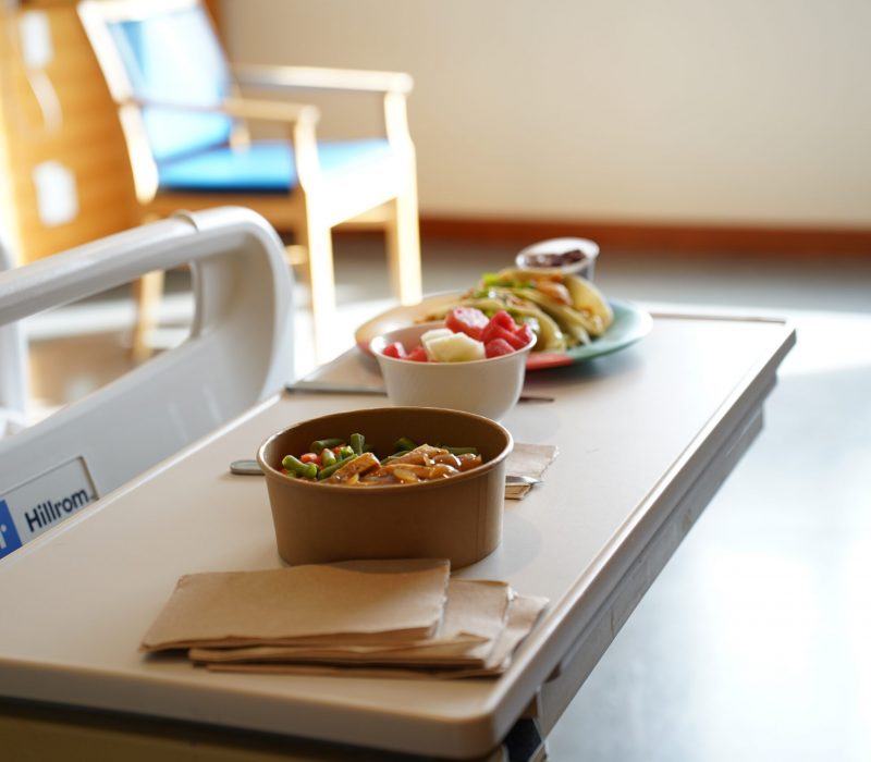 Bowls of food placed on a table in a hospital room.