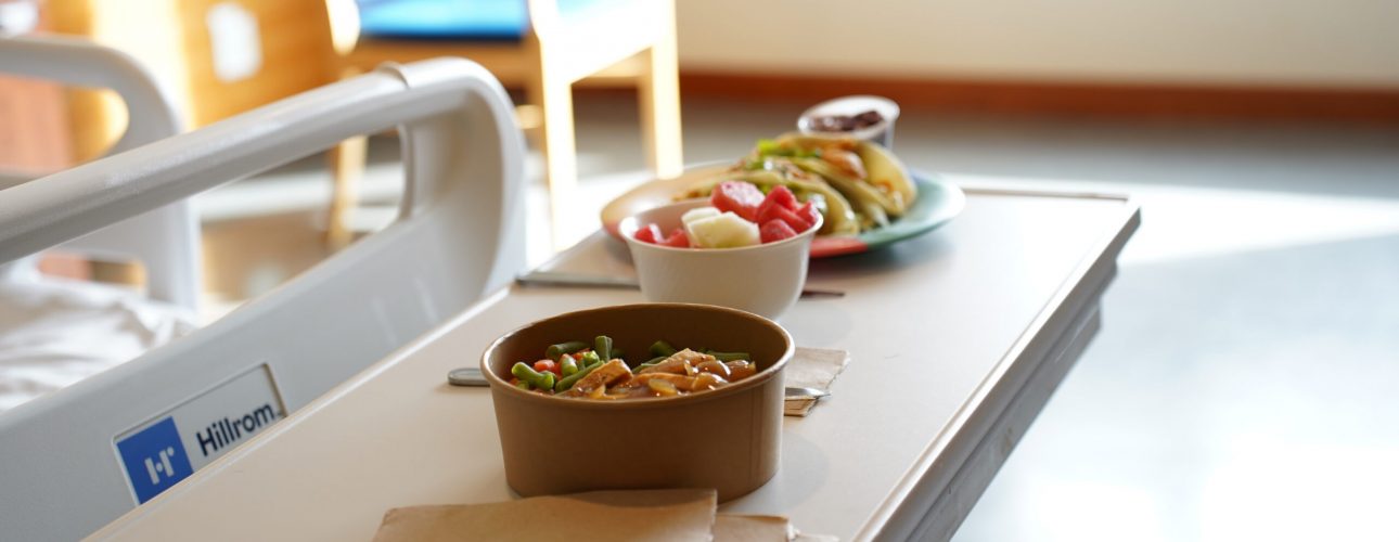Bowls of food placed on a table in a hospital room.