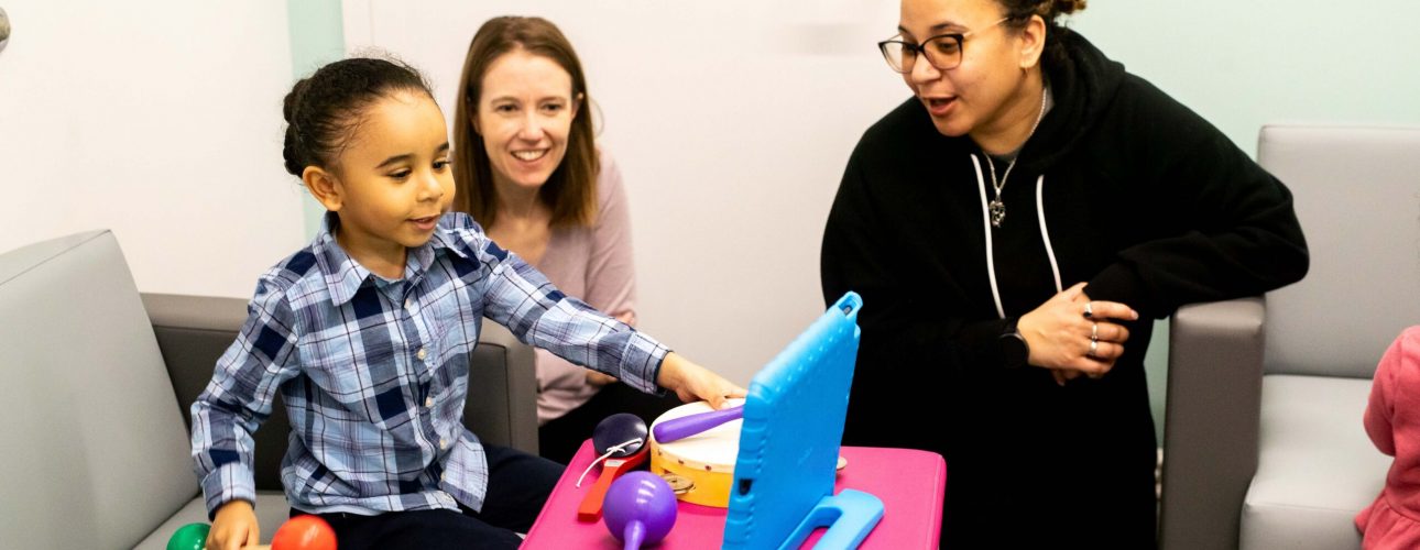 A child and two adults play a video game on a blue tablet