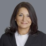 Poonam 2022 An adult wears a suit in front of a grey background