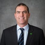 SB An adult wears a suit in front of a grey background