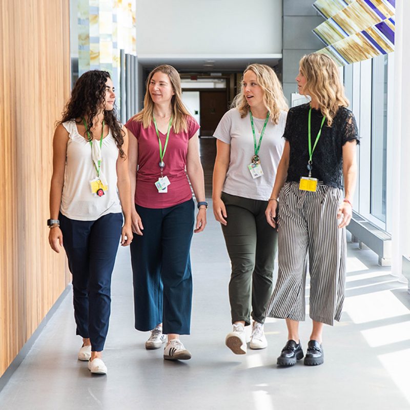 A group of adults walk together down a brightly-lit hospital hallway