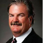 daniel mc An adult wears a suit in front of a grey background