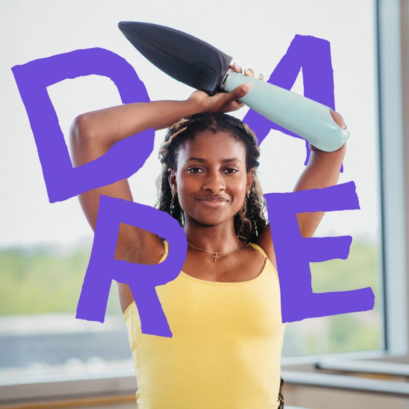 A young woman smiles and holds her arms above her head