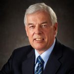 robinw An adult wears a suit in front of a black background